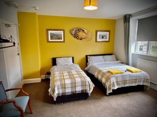 1 dormitorio con 2 camas y pared amarilla en The wrey arms inn en Barnstaple
