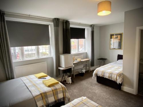 a room with two beds and a desk and two windows at The wrey arms inn in Barnstaple