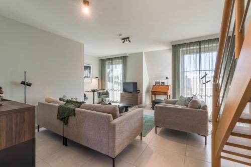een woonkamer met 2 banken en een televisie bij Smeysea - Stylish apartment in Sint-Idesbald in Sint-Idesbald