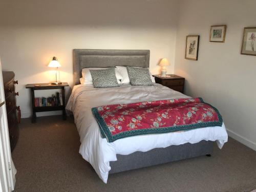 a bedroom with a large bed with a red blanket at Tremanhire Cottage in Solva