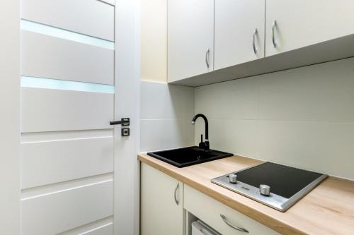 a kitchen with white cabinets and a sink at Niepodleglosci Studio in Sopot
