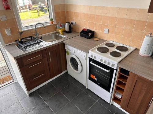 a kitchen with a washing machine and a sink at Semi-detached chalet - Uddingston, Glasgow in Uddingston