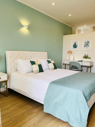a bedroom with a large white bed and a desk at Sunset Retreat 1a linha de mar in Monte Gordo