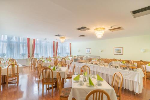 um salão de banquetes com mesas e cadeiras com toalhas de mesa brancas em Hotel Kindler 2,0 Self-Check-In em Leoben