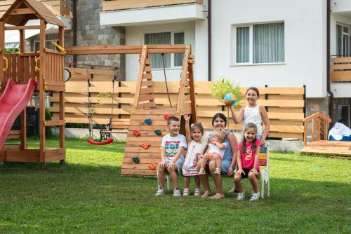 a group of children sitting on a chair in front of a playground at Villa Pino in Velingrad