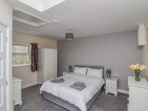 a bedroom with a large white bed and a window at Stable End Cottage in Spilsby
