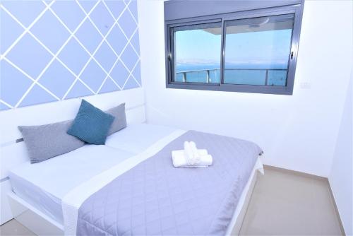 a white bedroom with a bed with a window at Yalarent Tiberias Ariston Apartments & Penthouse in Tiberias