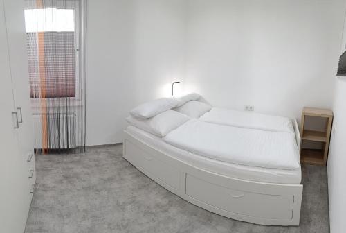 a white bedroom with a bed with white sheets at Glücks-Burg STERN in Glücksburg