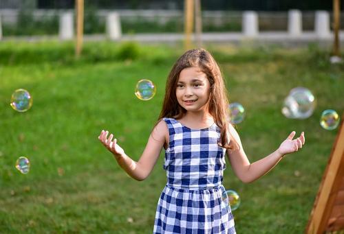 a little girl in a dress playing with bubbles at Villa Pino in Velingrad