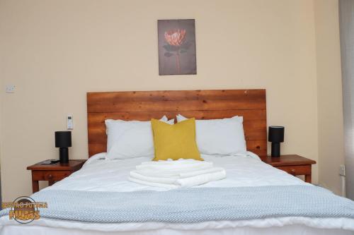 a bed with white sheets and yellow pillows at The Hill Bed and Breakfast in Francistown