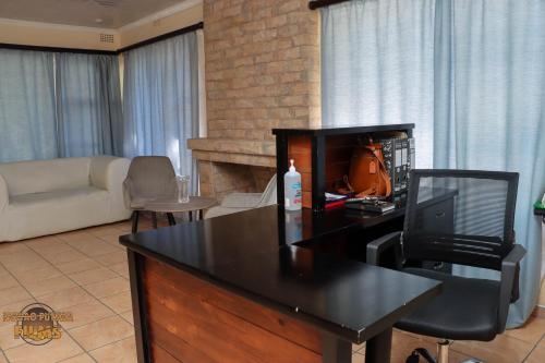 a living room with a couch and a desk with a television at The Hill Bed and Breakfast in Francistown
