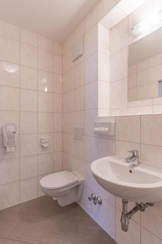 a white bathroom with a toilet and a sink at Hotel Kindler 2,0 Self-Check-In in Leoben