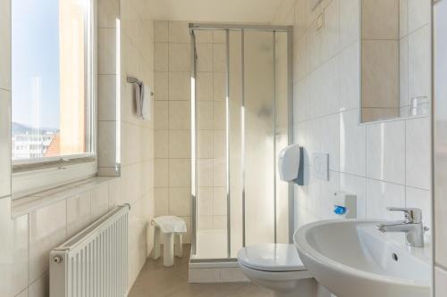 a white bathroom with a sink and a toilet at Hotel Kindler 2,0 Self-Check-In in Leoben