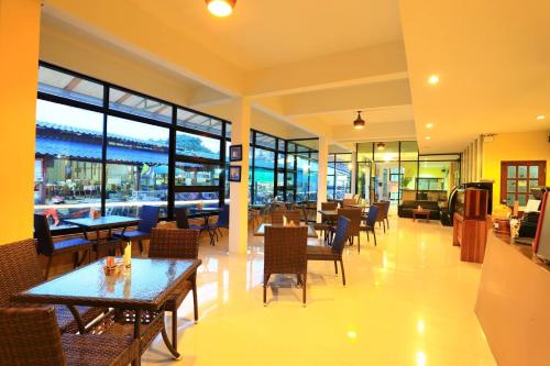 un ristorante con tavoli, sedie e finestre di Harmony Bed & Bakery a Koh Lipe
