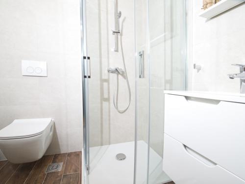 a white bathroom with a shower and a toilet at Apartments Hera in Mošćenička Draga
