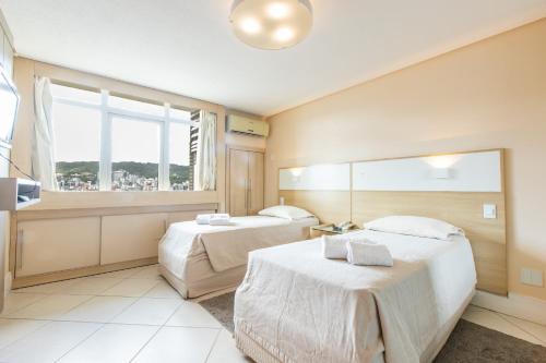 a hotel room with two beds and a window at Delupo Hotel - Livin Studios in Criciúma