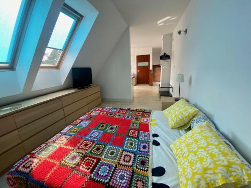a bedroom with a bed with a colorful quilt on it at Bursztynowa 16 Hel in Hel