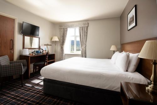 a hotel room with a large bed and a desk at The Coniston Inn - The Inn Collection Group in Coniston