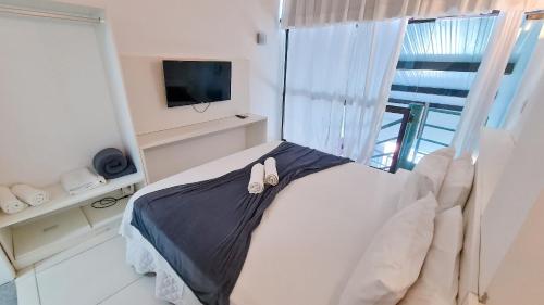 a bedroom with a bed and a tv and a window at Flat laguna Beach By Bispo in Porto De Galinhas