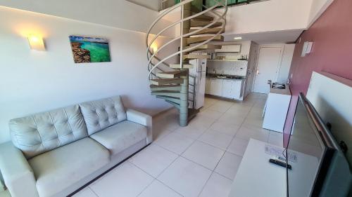 a living room with a couch and a spiral staircase at Flat laguna Beach By Bispo in Porto De Galinhas