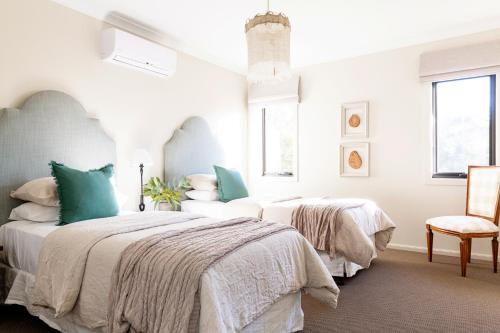 two beds in a white bedroom with a chair at River Run Bright in Bright