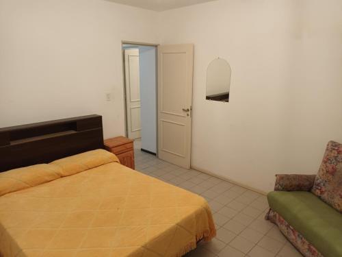 ein Schlafzimmer mit einem Bett, einem Stuhl und einem Spiegel in der Unterkunft Casa Los Lapachos in La Punta