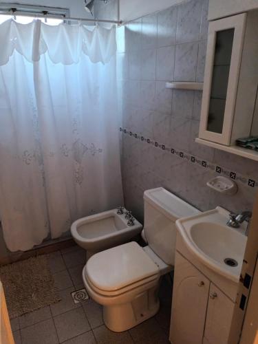 a white bathroom with a toilet and a sink at Casa Los Lapachos in La Punta