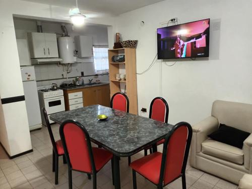 a kitchen and dining room with a table and red chairs at Casa Los Lapachos in La Punta