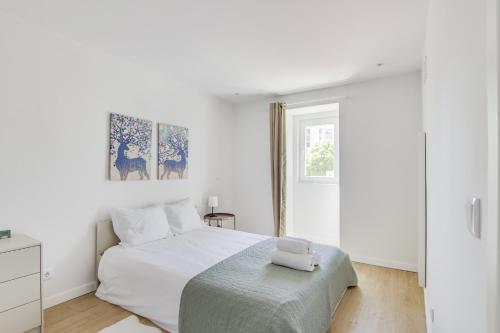 um quarto branco com uma cama branca e uma janela em Cruzeiro Charm Apartments em Lisboa