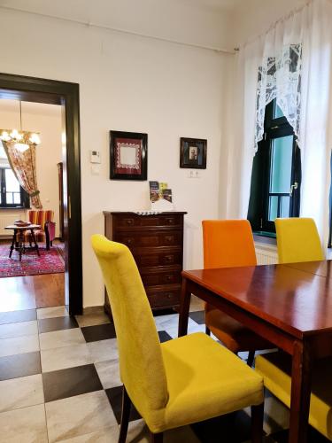 a dining room with a wooden table and yellow chairs at Kosbor Panzió in Magyarszombatfa