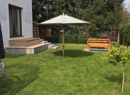 un banc en bois assis sous un parasol dans une cour dans l'établissement Villa na Zdrowiu, à Łódź