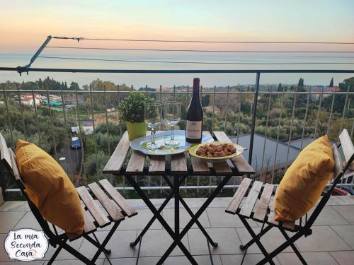 a table with a bottle of wine and a plate of food at La mia seconda casa ad Aci Castello in Aci Castello