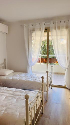 Duas camas num quarto com uma grande janela. em le meilleur de Cannes au palm beach em Cannes