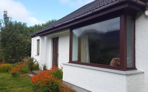 a large window on the side of a white house at Allt Slapin in Torrin