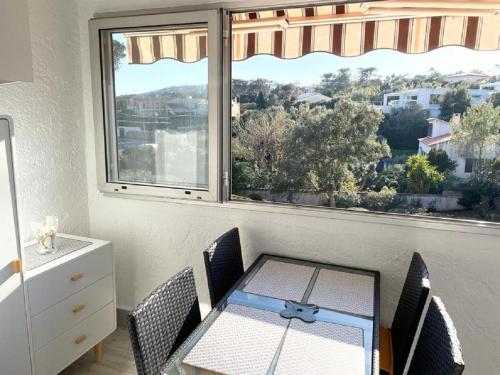 - une table à manger et des chaises dans une pièce avec fenêtre dans l'établissement Entre ST-RAPHAEL et ST-TROPEZ. Studio pieds dans l'eau, à partir de 600 Euros/semaine., à Saint-Aygulf