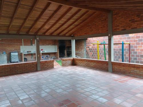 a large patio with a brick wall and a wooden ceiling at Cabaña y apartamentos in Chinácota