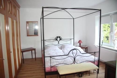 a bedroom with an iron canopy bed with a bench at Ferienwohnung Bellmann in Prinzenmoor