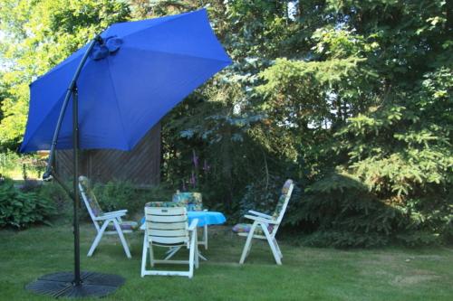 una sombrilla azul sentada junto a dos sillas y una mesa en Ferienwohnung Bellmann, en Prinzenmoor