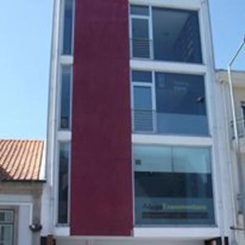 a tall building with windows and a red wall at APART 2 Alojamento Para Turismo e Negócios in Braga