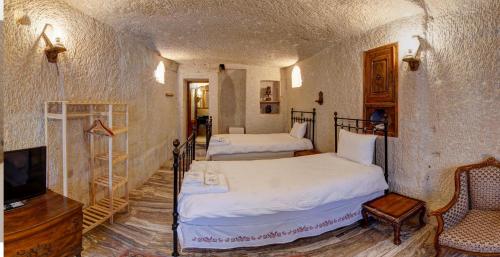a bedroom with two beds and a tv and a chair at Village Cave House Hotel in Goreme
