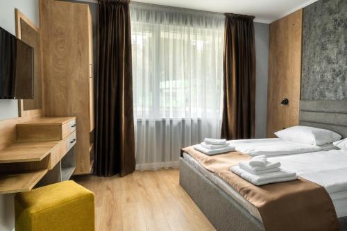 a hotel room with two beds and a television at Villa Pino in Velingrad