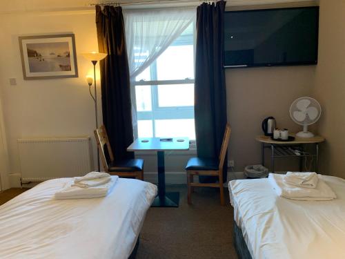 a hotel room with two beds and a desk and a window at The Royal Clarence Hotel (on the Seafront) in Burnham on Sea