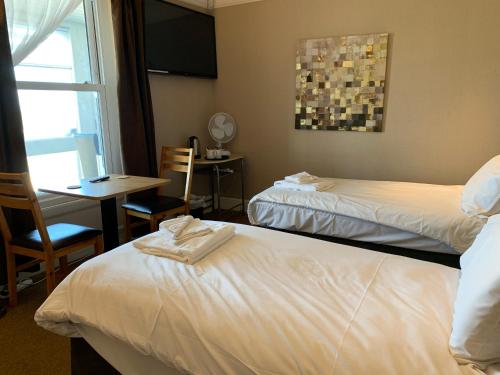 a hotel room with two beds and a table and a window at The Royal Clarence Hotel (on the Seafront) in Burnham on Sea