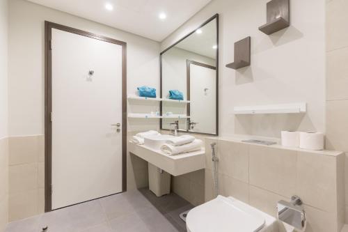 a bathroom with a sink and a toilet and a mirror at Revelton Apartment One Residence in Dubai