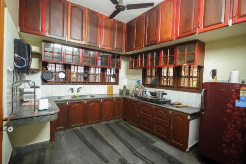 cocina con armarios de madera y nevera en NALINAM HOMESTAY en Thiruvananthapuram