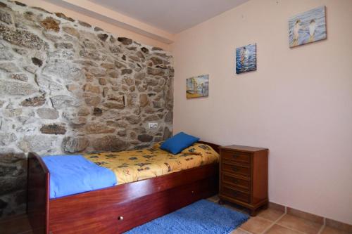 a bedroom with a bed and a stone wall at Casa Avoa María in Ourense