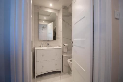 Baño blanco con lavabo y aseo en Luxury 1 bed studio at Florence House, in the centre of Herne Bay and 300m from beach en Herne Bay