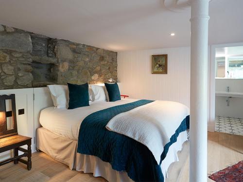 a bedroom with a large bed with a stone wall at Monachyle Mhor Hotel in Lochearnhead