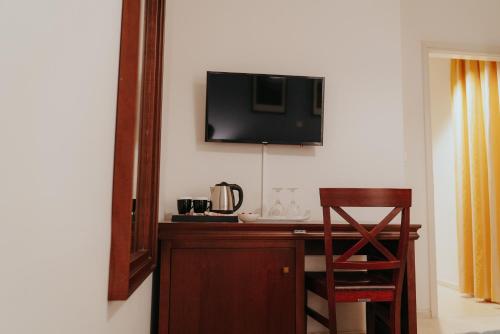 a desk with a chair and a television on a wall at 1909 Guesthouse in Kalavrita