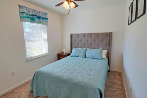 ein Schlafzimmer mit einem Bett mit blauer Decke und einem Fenster in der Unterkunft Jewell Cottage in Port Saint Joe
